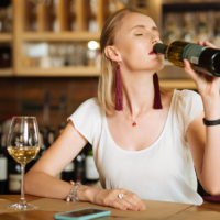 Nice young woman drinking lots of wine